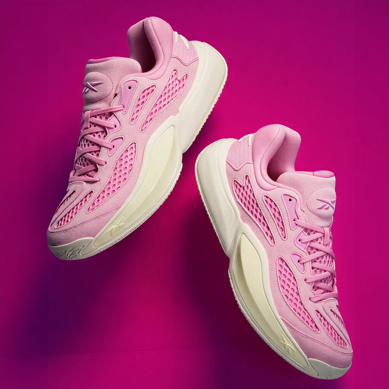 Two pink Reebok Engine A 26 Basketball Shoes with cream-colored soles are displayed against a vibrant pink background. Both shoes are facing slightly upward and to the right, showcasing their mesh and synthetic details designed for enhanced stability and impressive energy return.