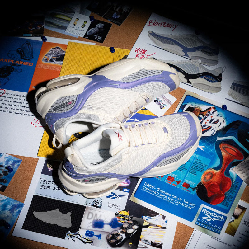 A pair of Women’s DMX Series 3000 Shoes by Reebok, in white and lavender, are displayed on a bulletin board filled with photos, design sketches, and notes related to sneaker development, highlighting their lightweight support and innovative DMX moving air technology.