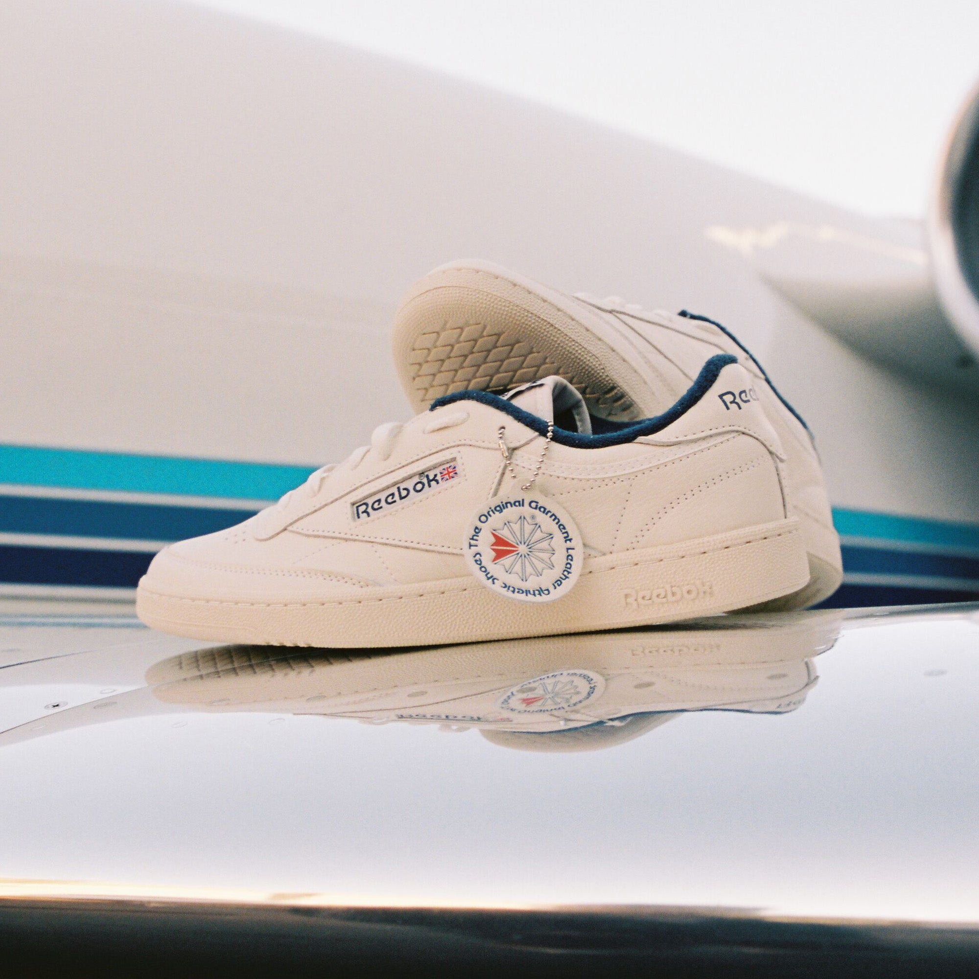 Beige Reebok sneaker on a reflective surface with a blurred background