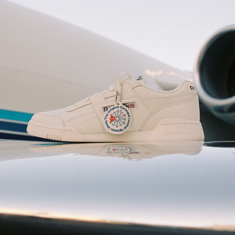 Beige sneaker with a circular patch on a reflective surface