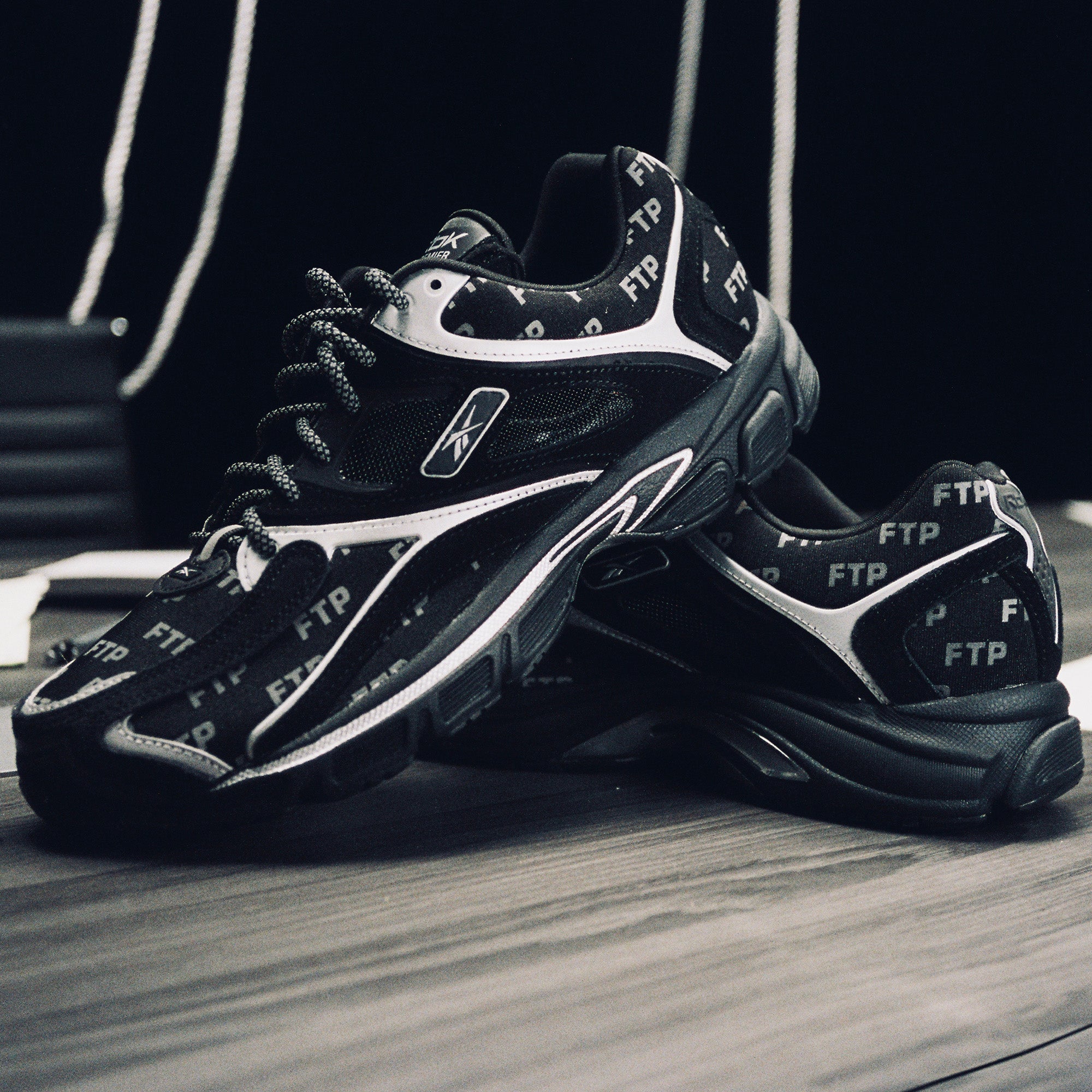 Black and white sneakers with visible branding on a wooden floor.