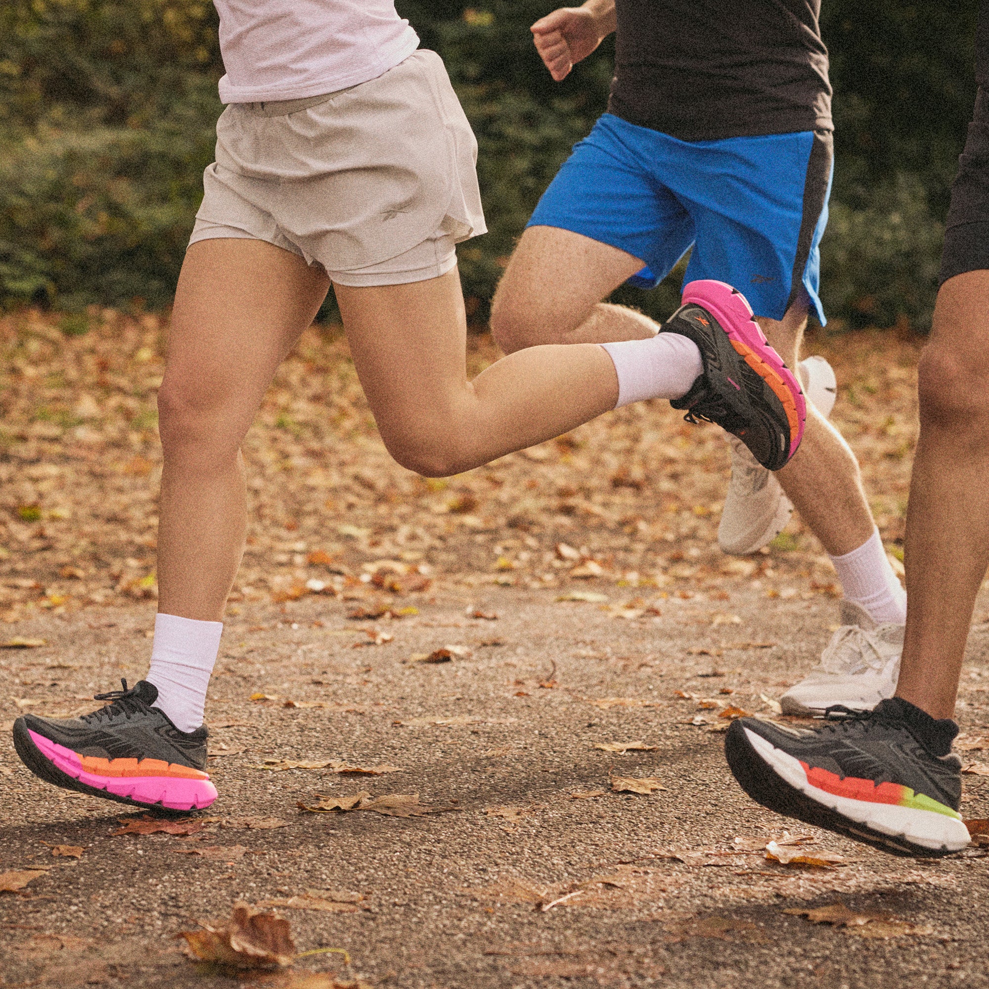 Three runners in motion on a leaf-covered path