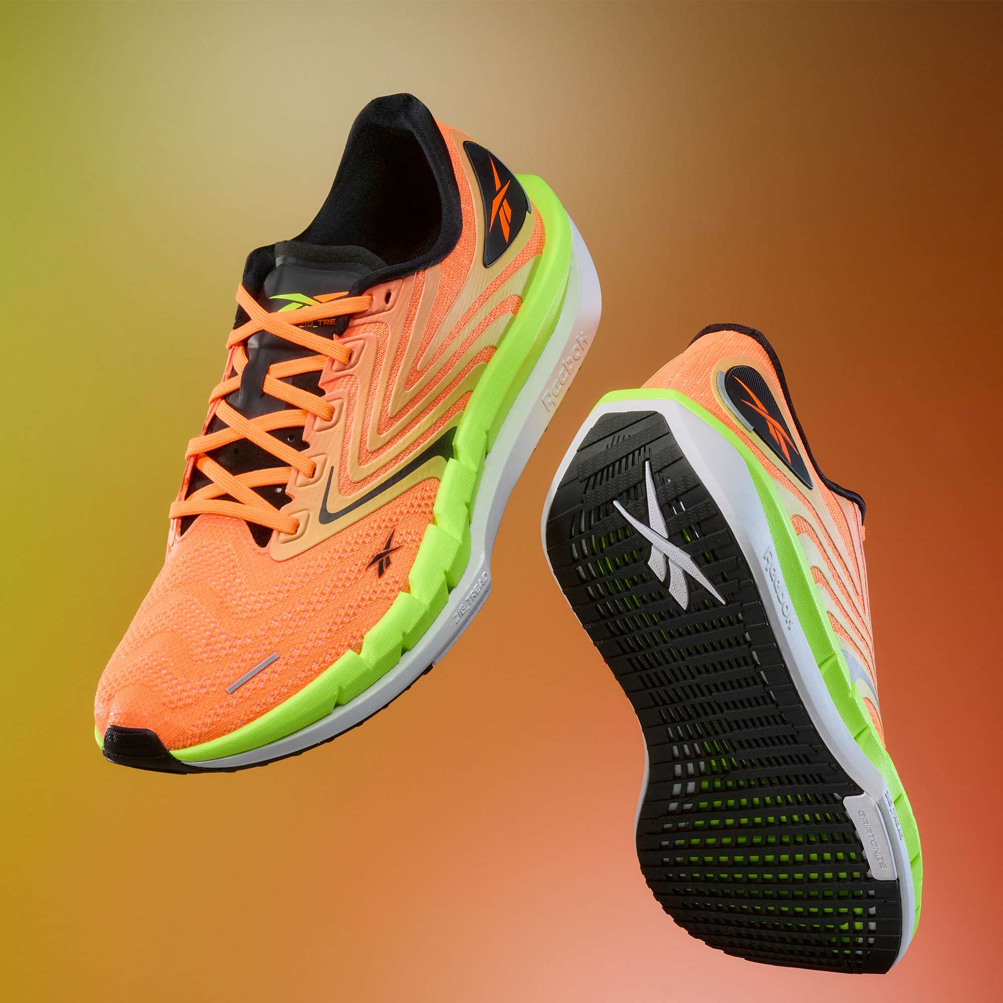 Two vibrant orange Reebok Men's FloatZig Tread Running Shoes with neon green accents and cushioned midsoles are displayed on a gradient brown-orange backdrop. One shoe reveals the top and side; the other features the sole—ideal for treadmill workouts.