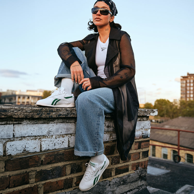 Person sitting on a rooftop with a cityscape background