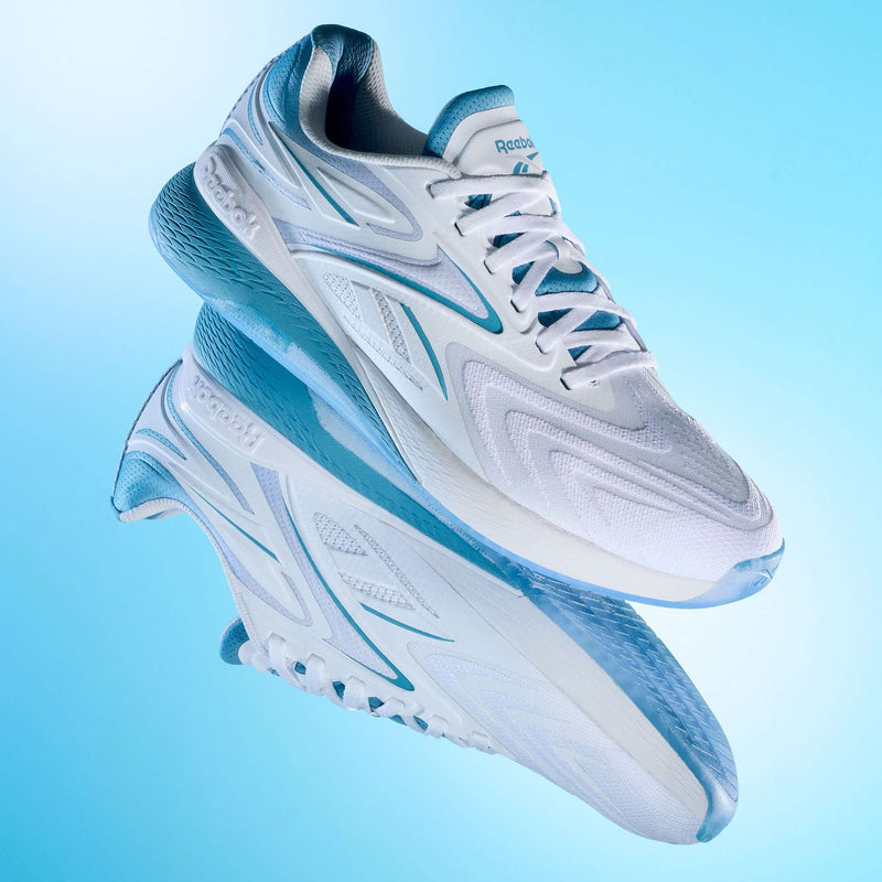 A pair of Reebok Nano X5 Edge Training Shoes in white and light blue are shown against a gradient blue background, with one shoe above its reflection, showcasing their sleek design and Flexweave-textured sole.