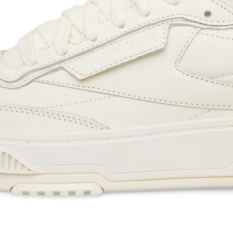 Close-up side profile of an off-white Reebok Club C LTD leather sneaker, highlighting the laces and thick rubber sole of this classic lifestyle shoe.