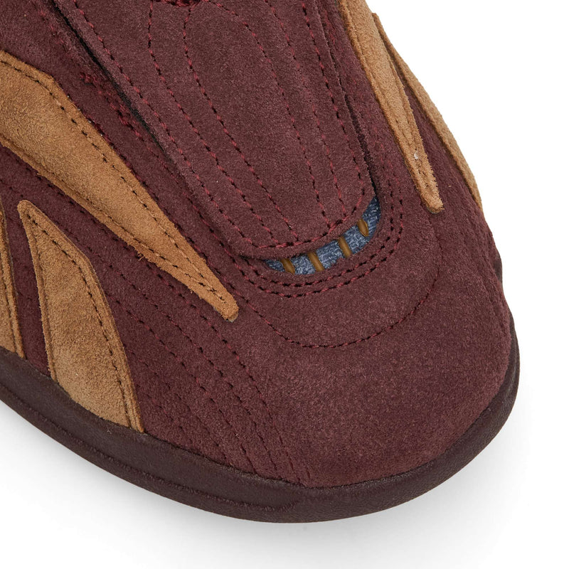 Close-up of the toe of a maroon and brown suede Reebok Hammer Pro LTD sneaker with decorative stitching.