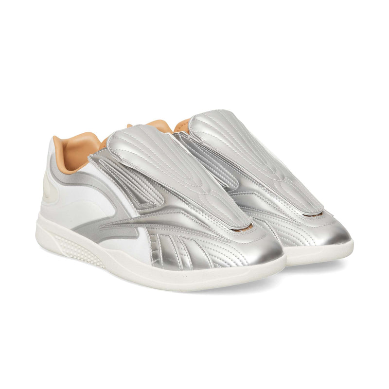 Reebok Hammer Pro LTD low-top sneaker in silver and white, featuring a prominent molded silver overlay across the laces, a tan interior lining, and a durable rubber sole.