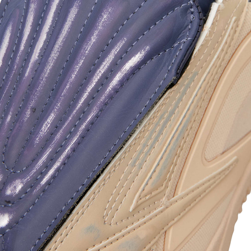 Close-up of Reebok Hammer Pro LTD sneakers featuring a glossy, ribbed purple panel next to a tan, angular leather upper section.