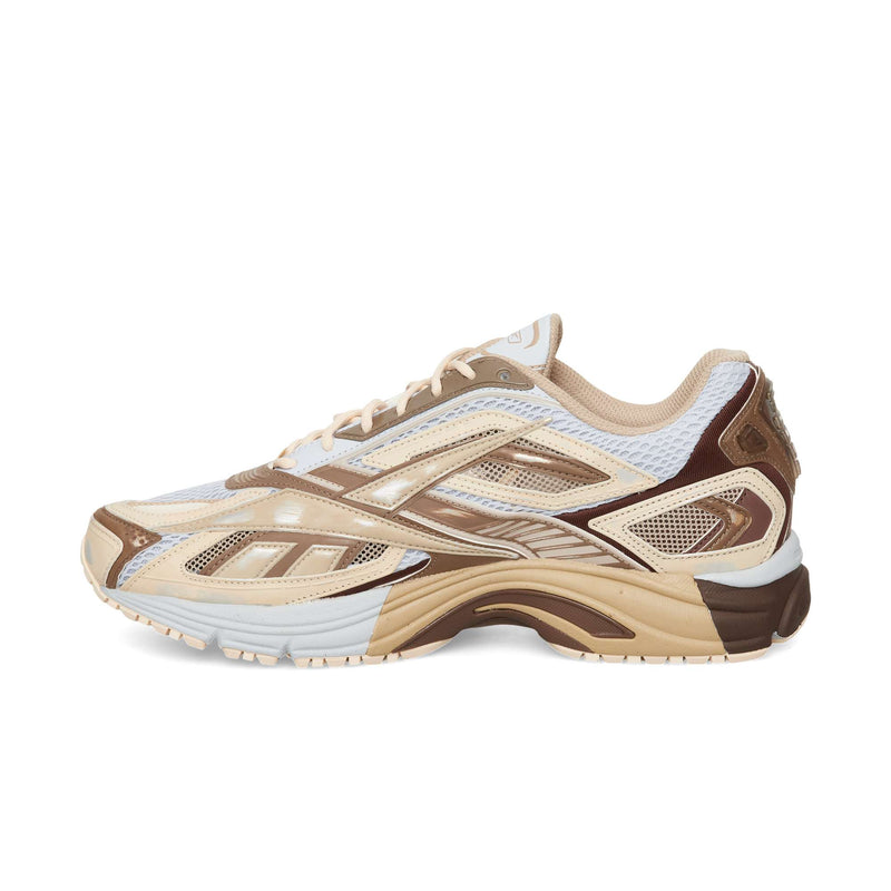 Reebok Premier Road Ultra low-top running sneaker in shades of beige, white, and brown with a mesh upper, layered synthetic overlays, and a thick, lugged rubber sole.