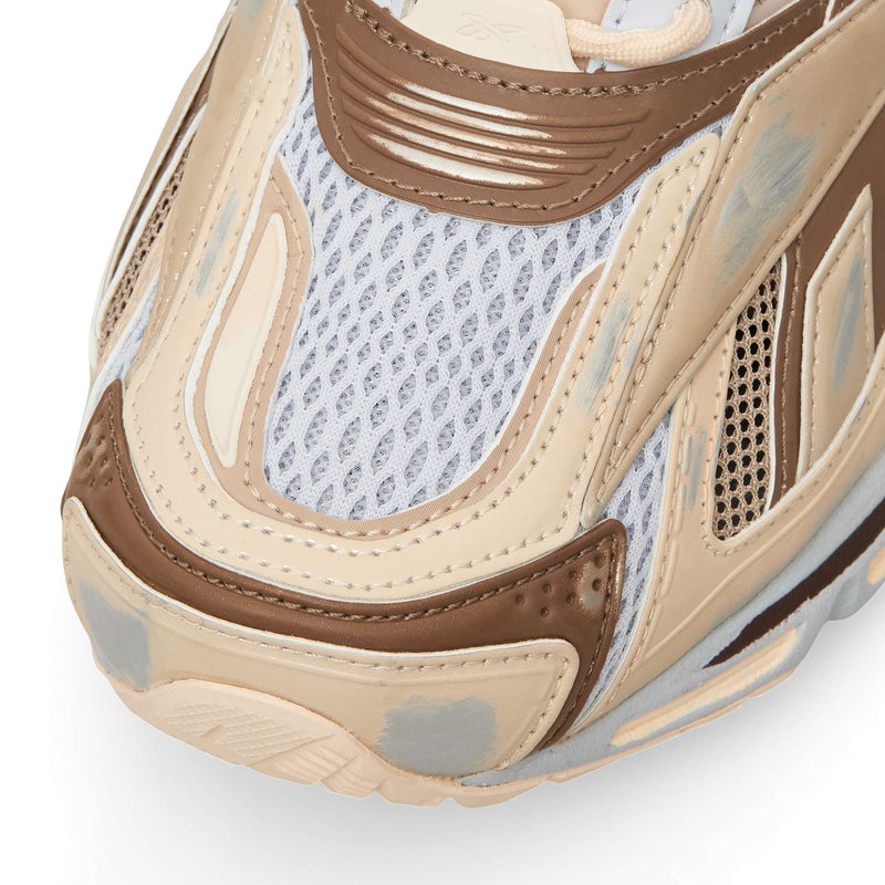 Close-up of the Reebok Premier Road Ultra toe box, featuring tan, brown, and white mesh construction with distressed paint-like detailing.
