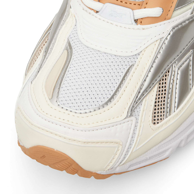 Close-up of a white, silver, and tan Reebok Premier Road Ultra running sneaker, featuring mesh paneling and a textured rubber sole.