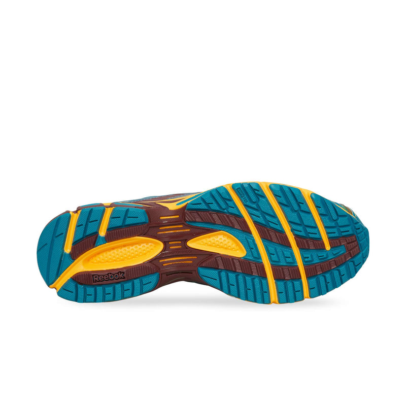 The underside of a Reebok Premier Road Ultra sneaker featuring a blue, yellow, and brown lugged rubber sole.