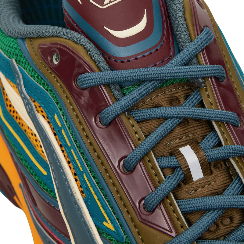 Close-up of a Reebok Premier Road Ultra sneaker showing the laces, tongue, and layered panels in green, maroon, yellow, and blue.