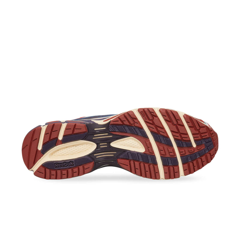 The rubber outsole of a Reebok Premier Road Ultra running sneaker featuring a multi-directional tread pattern in shades of red, cream, and dark blue.