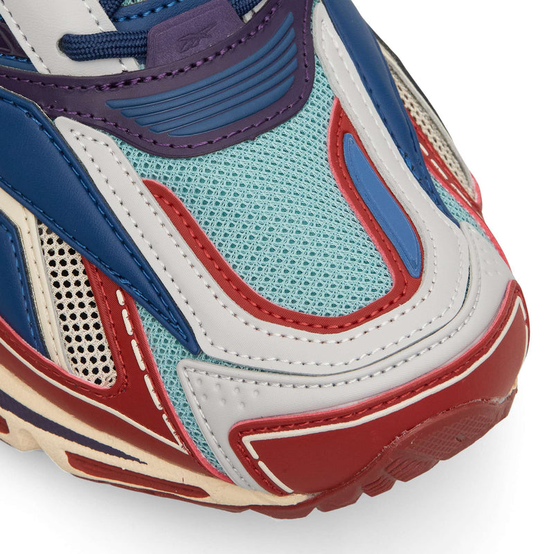 Close-up of a Reebok Premier Road Ultra featuring layered panels of blue, light blue mesh, red, and off-white.