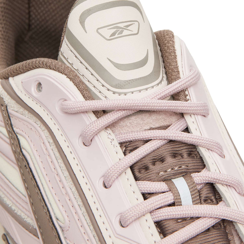 Close-up of a pale pink and brown Reebok Premier Road Ultra athletic sneaker with matching laces and a logo on the tongue.