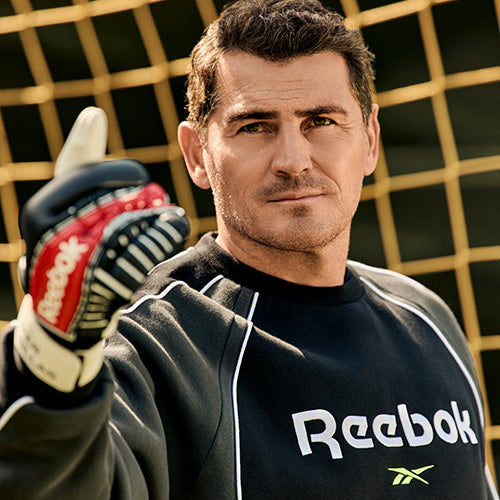 Man wearing a Reebok shirt and gloves, holding a sports ball with a grid background