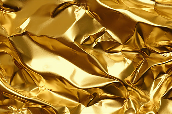 A close-up of crumpled metallic gold material with a shiny, reflective surface.