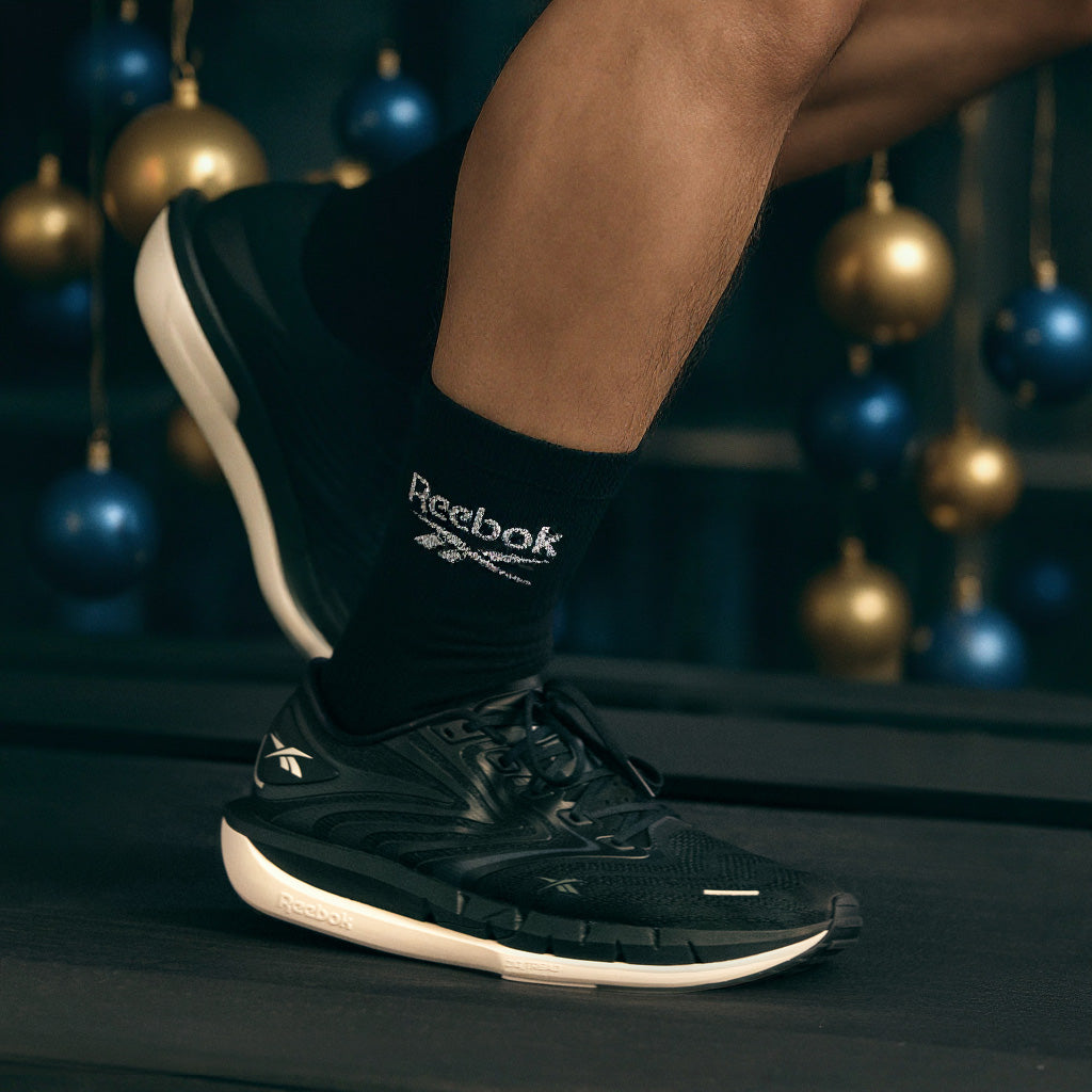 man running on treadmill with black reebok socks and black and white sneakers