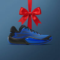 A blue and black athletic sneaker shown in side profile against a dark blue background, with a large red gift bow hanging above it.