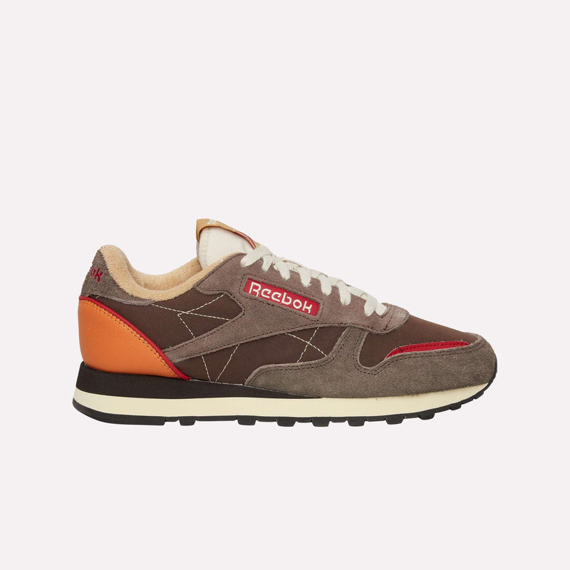 A pair of Reebok Classic Leather Premium LTD Shoes in brown and gray with a red logo, orange heel accent, beige laces, and a black sole is displayed in side profile against a plain white background. These retro sneakers feature a classic silhouette that embodies timeless style.