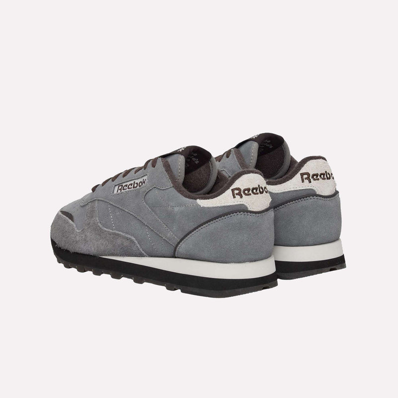 A pair of gray Reebok Classic Leather Premium LTD Shoes featuring white midsoles, black outsoles, and a mix of suede and mesh accents, displayed from a rear angle against a plain white background. This retro-inspired shoe boasts the timeless Classic Leather silhouette from Reebok.