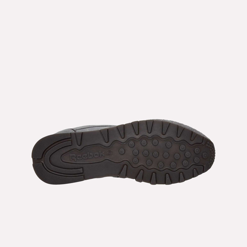 The image displays the black rubber sole of a Reebok Classic Leather Premium LTD Shoe, viewed from underneath. The outsole showcases a combination of circular and rectangular traction patterns, with the Reebok logo visible in the center—highlighting the classic retro silhouette of these iconic sneakers.