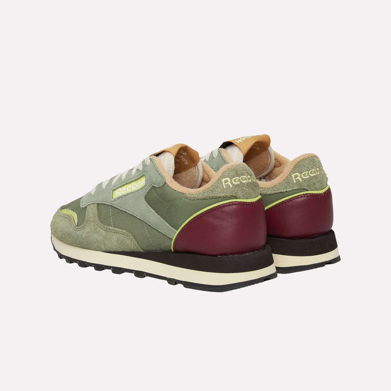 A pair of green and beige Reebok Classic Leather Premium LTD Shoes with burgundy heels and black soles, shown from the back and side on a plain white background. These sneakers highlight a classic silhouette and retro charm.