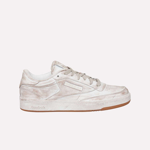 The Reebok Club C 85 Vintage LTD Shoes are shown in side profile against a plain white background, featuring a beige colorway with white laces, a perforated toe, brown rubber sole, and intentionally worn, distressed finish—an iconic lifestyle classic inspired by vintage tennis sneaker design.