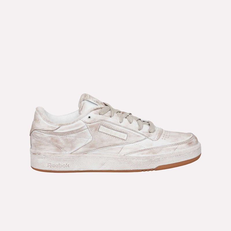 The Reebok Club C 85 Vintage LTD Shoes are shown in side profile against a plain white background, featuring a beige colorway with white laces, a perforated toe, brown rubber sole, and intentionally worn, distressed finish—an iconic lifestyle classic inspired by vintage tennis sneaker design.