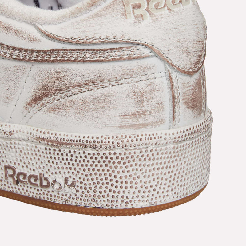 Close-up of the heel of a worn white Reebok Club C 85 Vintage LTD shoe, a classic lifestyle sneaker, featuring textured details and visible scuff marks on the leather upper and sole.