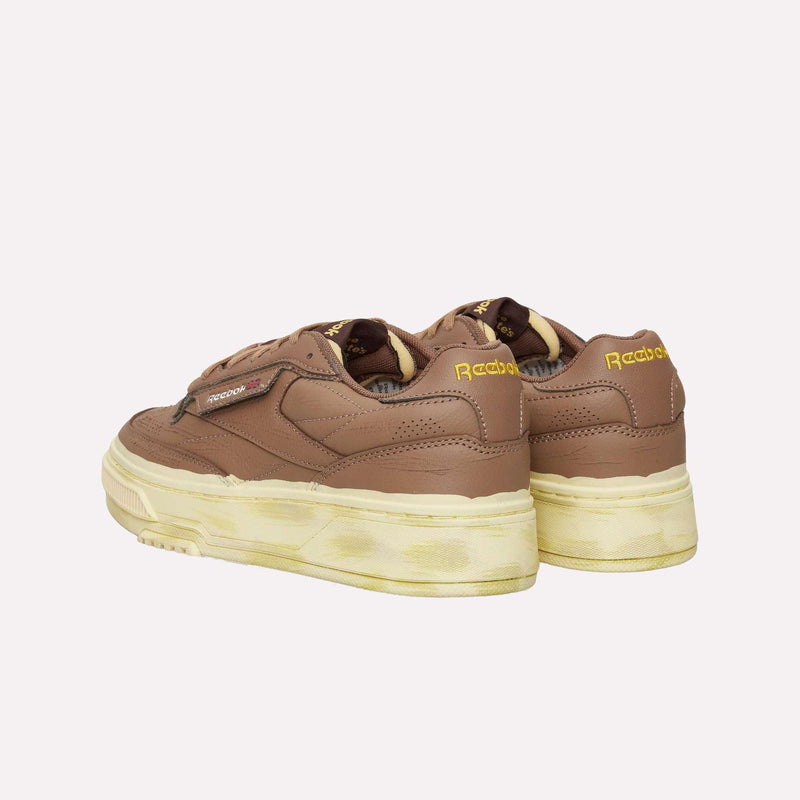 Brown Reebok Club C LTD Shoes with yellowed, worn-effect soles and yellow Reebok branding on the heel, displayed from a rear angle against a white background—a lifestyle classic that blends timeless tennis shoe style with everyday comfort.
