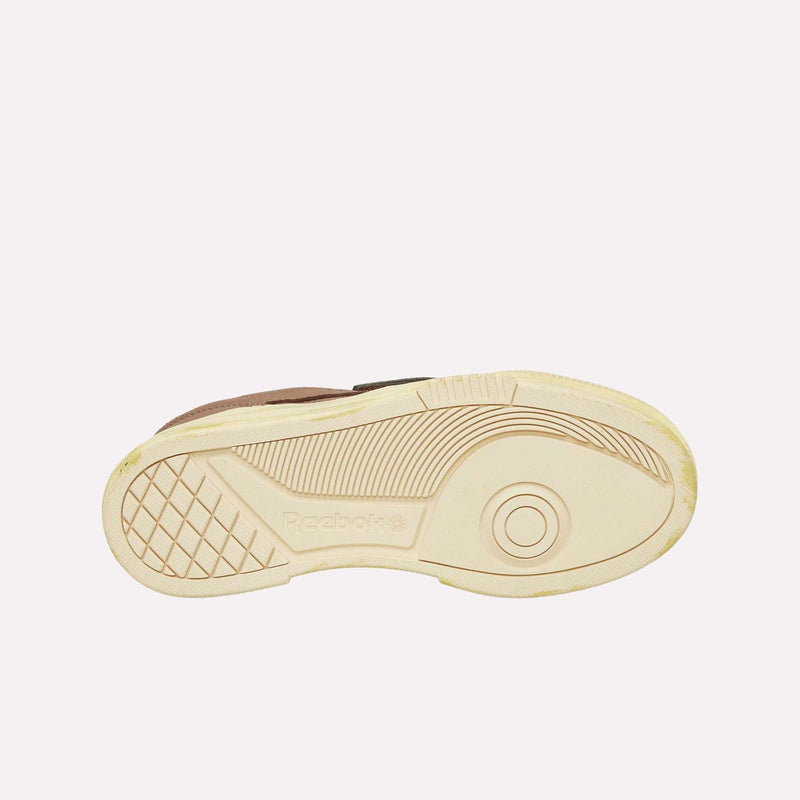 The image shows the beige sole of a Reebok Club C LTD Shoe, viewed from the bottom, featuring the Reebok logo and a textured traction pattern with curved lines and a grid section—a true lifestyle classic.