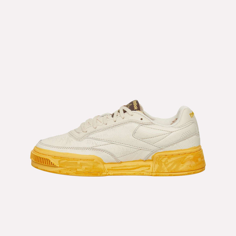 The Reebok Club C LTD Shoes are displayed from the side against a plain white background, showcasing their cream-colored upper inspired by classic lifestyle design, along with a textured, bright yellow sole and yellow accents.