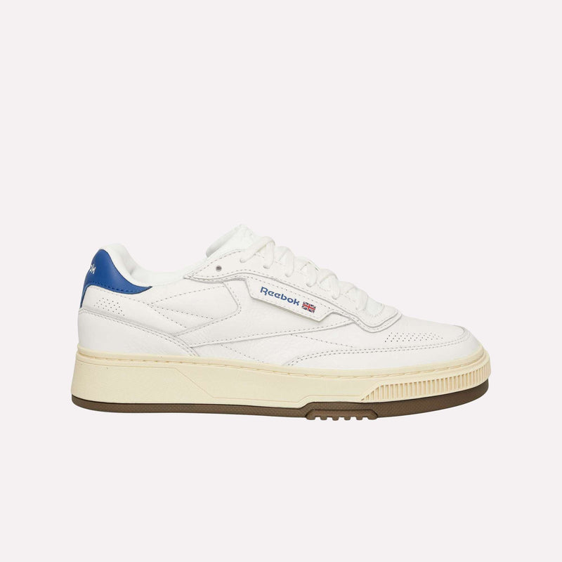 A side profile view of the Reebok Club C LTD Shoes in white, featuring a blue heel accent, tan midsole, and gum outsole—ideal for anyone looking for a classic lifestyle tennis sneaker.