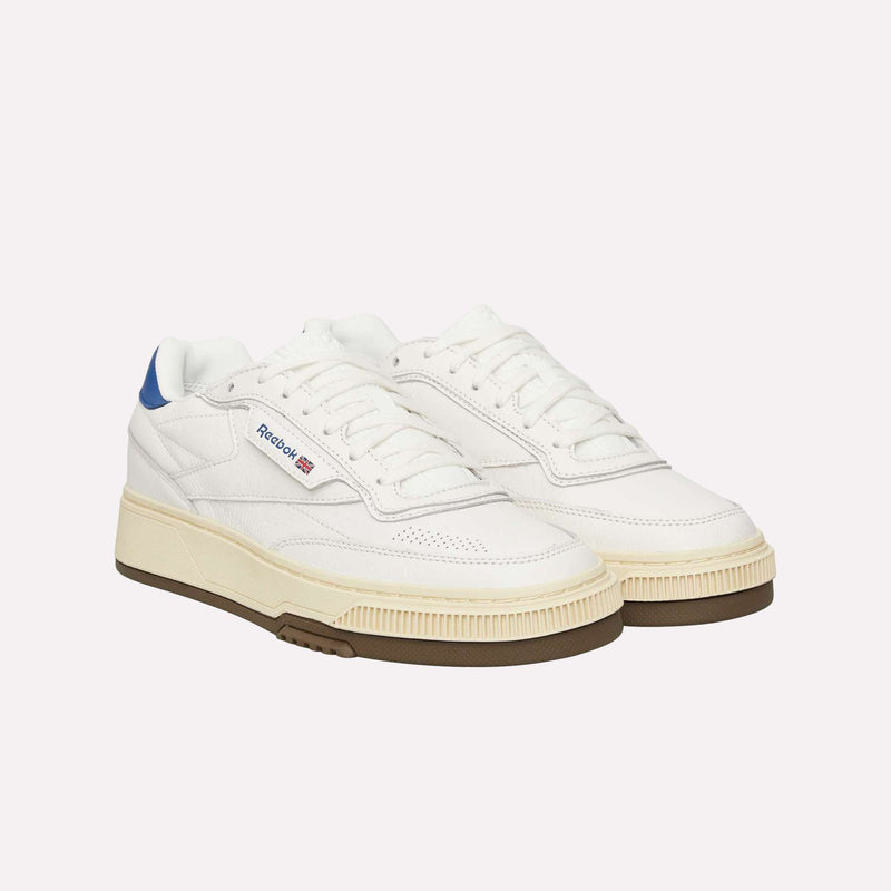 A pair of Reebok Club C LTD Shoes in white with beige soles, blue heel accents, and gum outsoles, displayed against a plain white background—these classic lifestyle sneakers from Reebok effortlessly combine timeless style with everyday versatility.