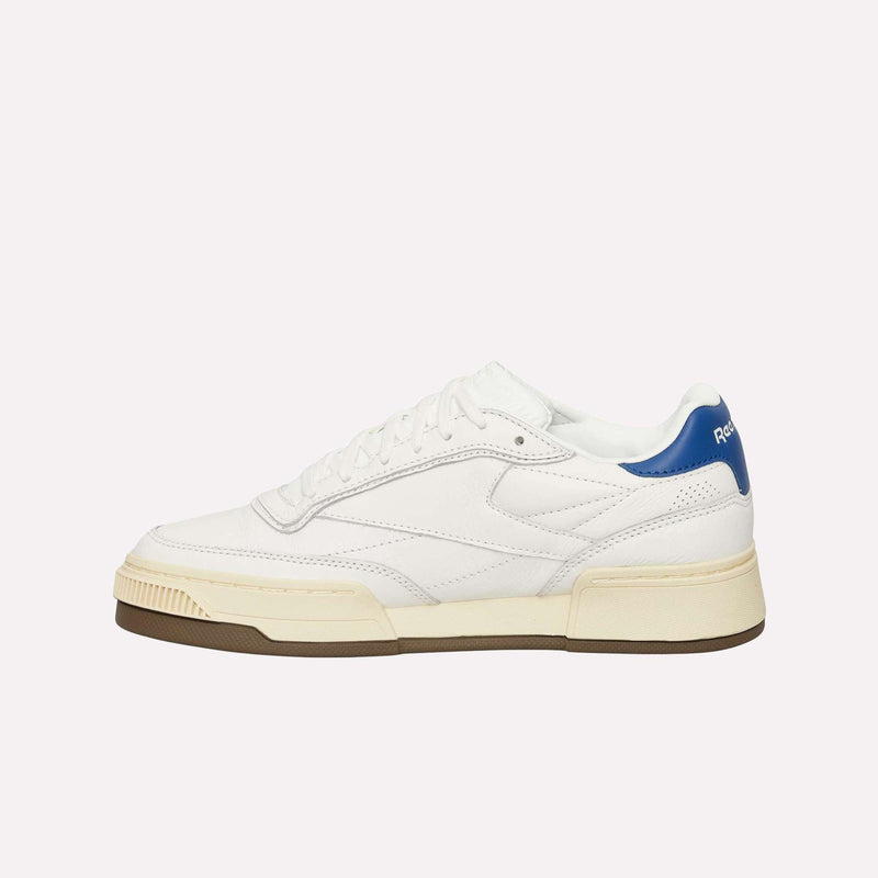 A side profile view of the Reebok Club C LTD Shoes displays their white upper, blue heel accent, cream midsole, and brown outsole against a plain background, showcasing this lifestyle classic.