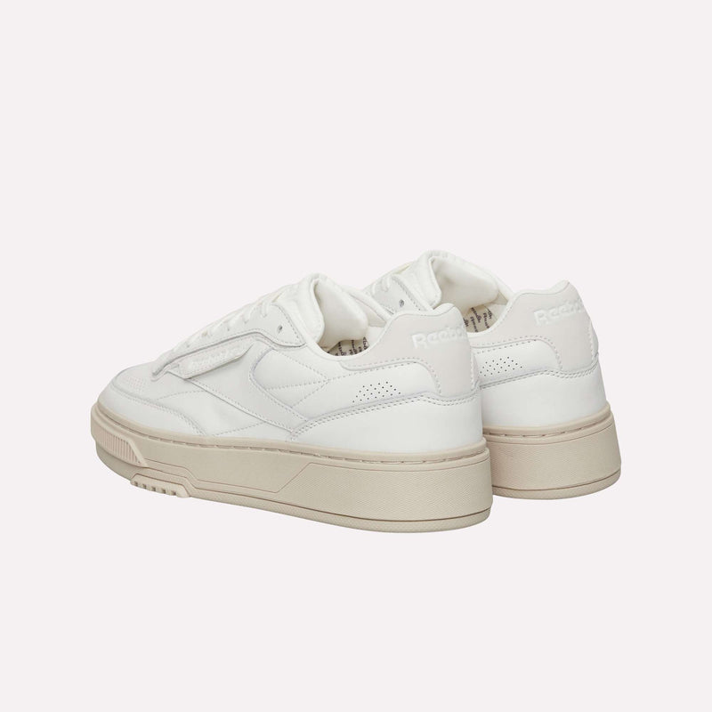A pair of Reebok Club C LTD Shoes in white with beige soles are arranged on a light background, angled to highlight both the sides and back. This lifestyle classic from Reebok blends timeless design with subtle elegance.