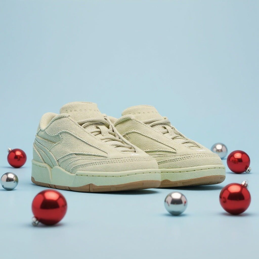 Beige sneaker on a light blue background with red and silver Christmas ornaments.