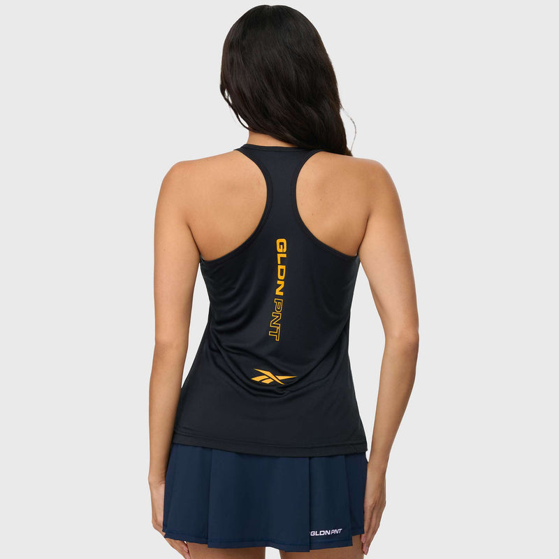 A woman with long, dark hair is seen from behind wearing a navy Reebok x GLDN PNT Women’s Tank Top featuring yellow text and a logo, along with a matching skirt, set against a plain light gray background.