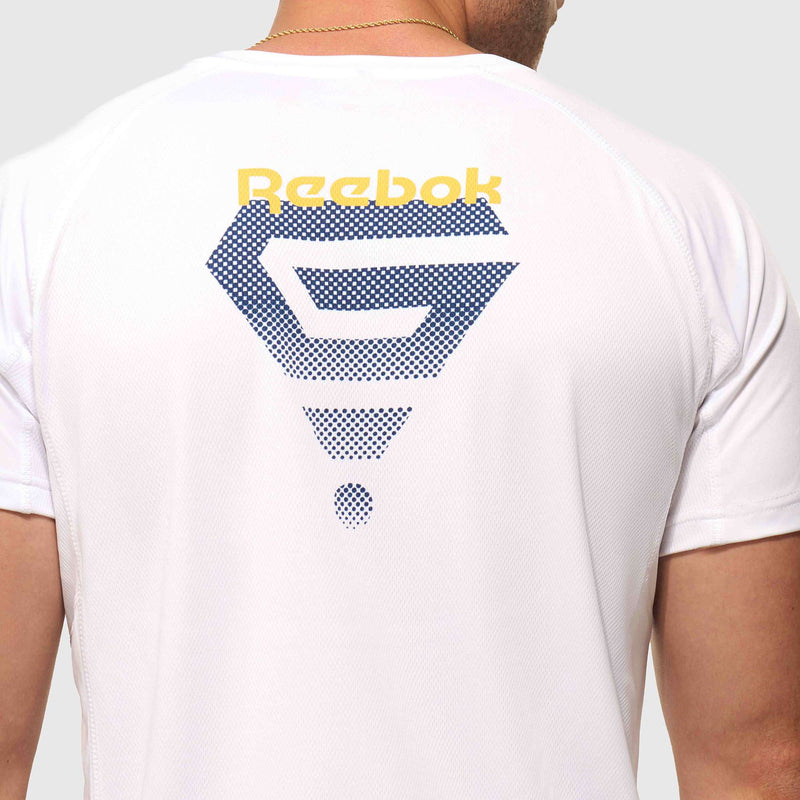 A man, seen from the back, wears a Reebok x GLDN PNT Tech Tee with a large blue geometric graphic and a yellow Reebok logo on the upper back.