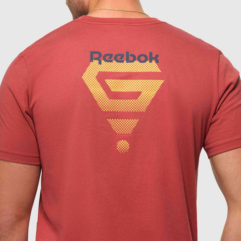 The back of a person wearing the Reebok x GLDN PNT Jersey Tee, a red premium cotton t-shirt by Reebok, showcases a yellow geometric design with the brand's black logo near the upper back.