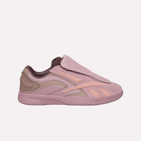 A side view of the Reebok Hammer Pro LTD Shoes in pink and mauve, featuring a covered lace area, textured suede upper, and distinctive wavy accents, displayed against a simple light backdrop.