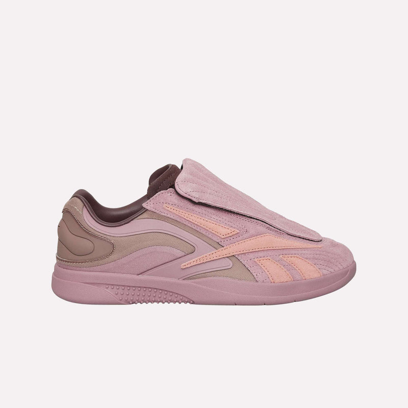 A side view of the Reebok Hammer Pro LTD Shoes in pink and mauve, featuring a covered lace area, textured suede upper, and distinctive wavy accents, displayed against a simple light backdrop.