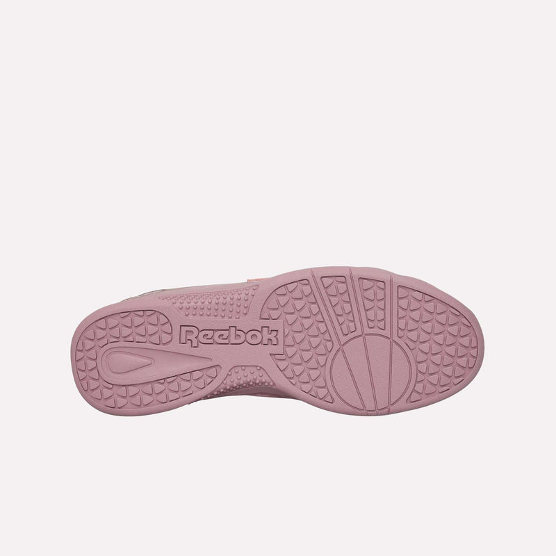 The image features the pink sole of the Reebok Hammer Pro LTD Shoes seen from below, highlighting the textured tread pattern and the Reebok logo embossed at the center. The durable rubber outsole provides lasting wear, perfectly complementing the stylish suede upper.