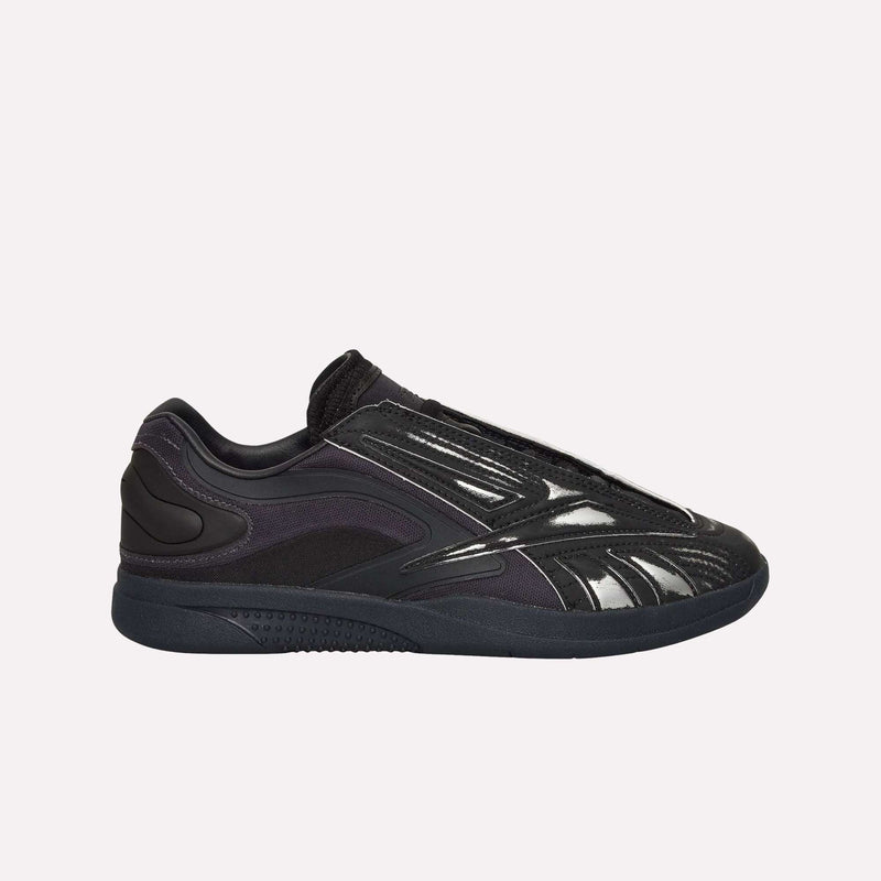 A black low-top shoe with matte and glossy finishes, the Hammer Pro LTD Shoes by Reebok showcase layered paneling and a sleek, modern silhouette crafted from high-quality faux leather. Photographed against a plain light background, their durable rubber sole is highlighted for lasting comfort and wear.