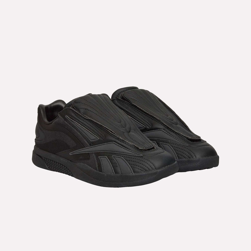 A pair of Reebok Hammer Pro LTD Shoes in black, featuring a futuristic layered design and a sturdy rubber sole, displayed against a plain white background.