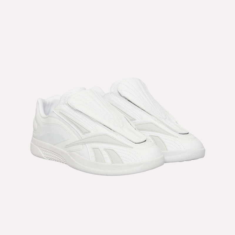 A pair of Hammer Pro LTD Shoes by Reebok, featuring a futuristic white design with sleek layered panels and a covered tongue, expertly crafted from premium faux leather and displayed on a plain white background. These shoes are completed with a durable rubber sole for lasting comfort and style.