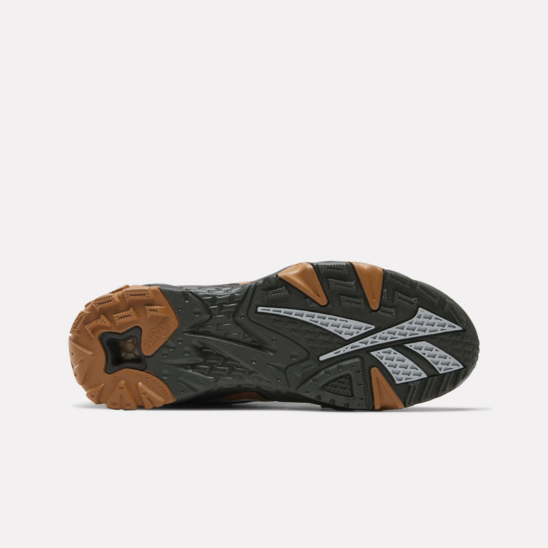 The image displays the bottom view of the Reebok x Market Preseason 94 Low Shoes, featuring a black, gray, and brown tread pattern and a large stylized logo in the center—reflecting the bold design characteristic of Reebok’s Preseason Collection.